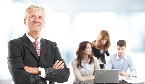 Preview: Executive Businessman Standing At Office While Business People Working On Laptop At Background