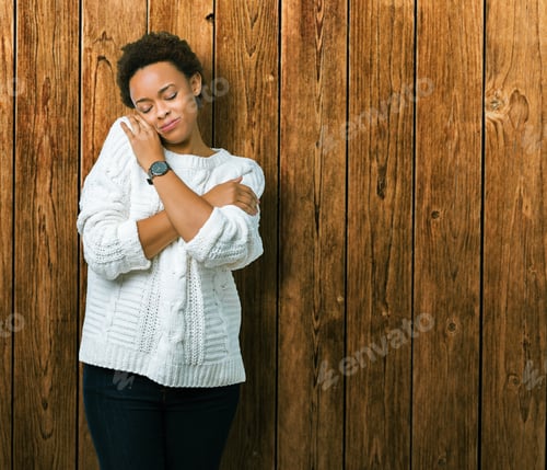 Preview: Beautiful Young African American Woman Wearing Sweater Over Isolated Background Hugging Oneself