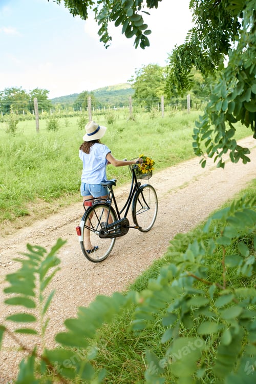 Preview: Rear View Full Length Portrait Of Young Woman Wearing Straw Hat And A Casual Clothing While Pushing