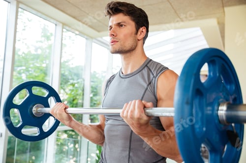 Preview: Serious Young Fitness Man Lifting Barbell In Gym