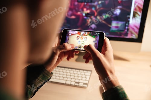 Preview: Closeup Of Man Playing Videogame On Smartphone In The Evening At Home