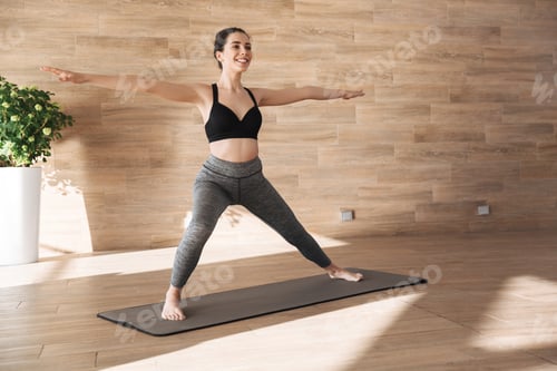Preview: Portrait Of A Happy Young Sportswoman Doing Stretching Exercises While Standing On A Fitness Mat At