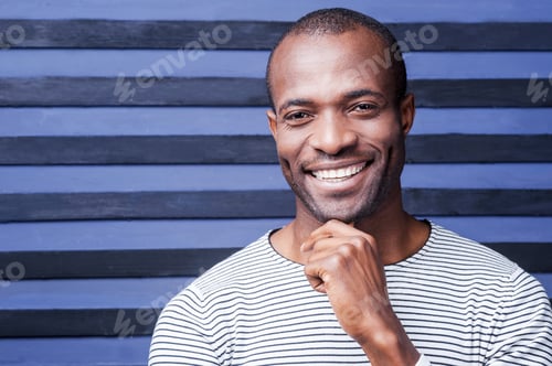 Preview: I Think I Like You. Happy Young African Man Holding Hand On Chin And Smiling While Standing Against