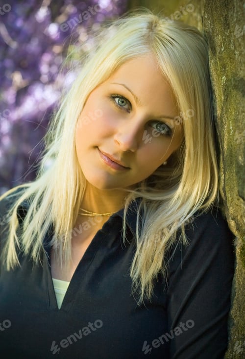 Preview: Relaxed Young Blond Girl Posing In The Park With Lilac Spring Flowers In The Background.