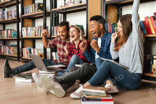 Preview: Picture Of Young Happy Students Sitting In Library On Floor Using Laptop Computer. Looking Aside