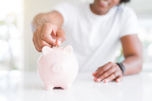 Preview: Close Up Of African American Man Saving Money Putting A Coin Inside Piggy Bank