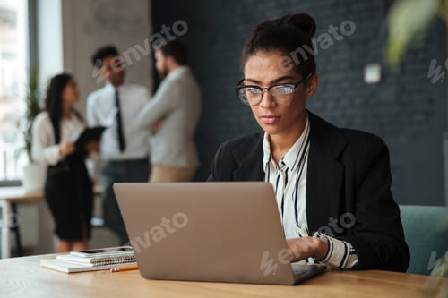Vista previa: Foto de una joven empresaria africana concentrada sentada en el interior con una computadora portátil.
Buscando