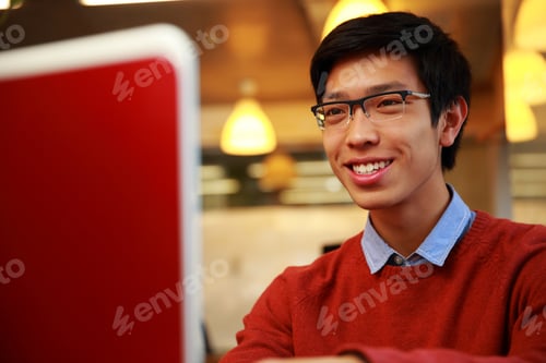 Preview: Happy Young Asian Man Looking At Laptop Screen