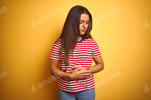 Preview: Young Beautiful Woman Wearing Striped T-Shirt Standing Over Isolated Yellow Background With Hand On