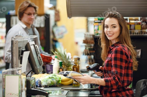 Preview: Picture Of Smiling Cashier Woman On Workspace In Supermarket Shop. Looking At Camera.