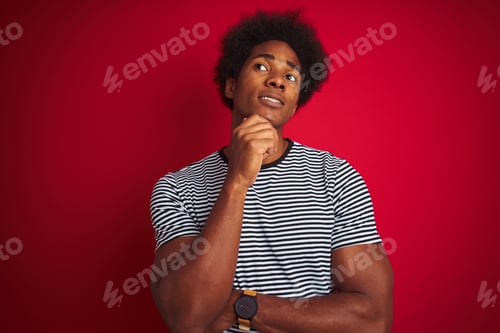 Preview: Young American Man With Afro Hair Wearing Navy Striped T-Shirt Over Isolated Red Background With