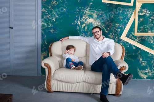 Preview: Happy Man And His Arms Embrace His Son. Family Mod On The Sofa At Home. White Shirt. Father'S Day