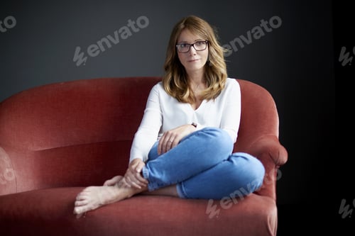 Preview: Full Length Shot Of An Attractive Middle Aged Woman Relaxing On Sofa While On Grey Background.
