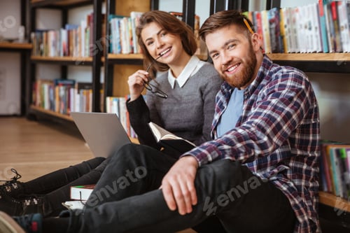 Preview: Young Couple Of Cheerful Students Sitting On The Floor And Studying In The University Library