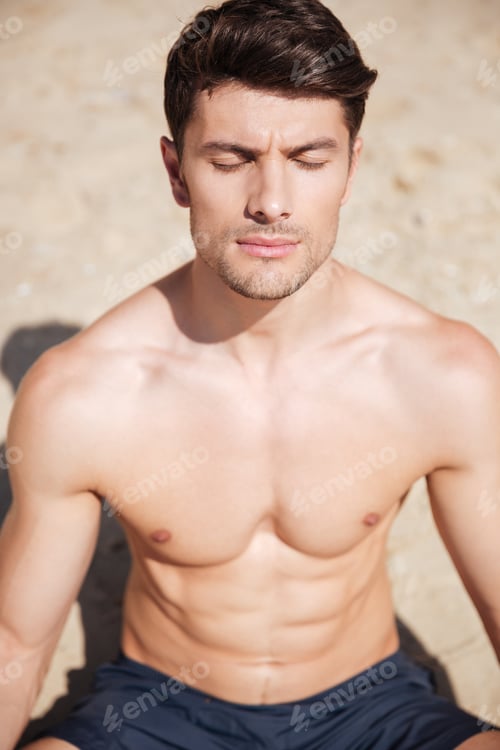 Preview: Closeup Of Attractive Young Man With Eyes Closed Meditating On The Beach