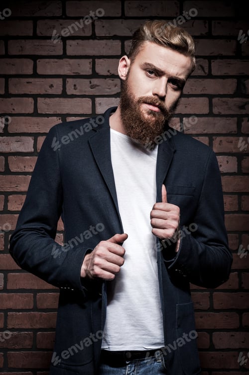 Preview: Cool And Trendy. Handsome Young Bearded Man Adjusting His Jacket And Looking At Camera While