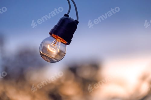 Preview: Glowing Lightbulb Against Soft Sunset Sky