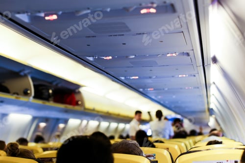 Preview: Blurred Photo Of Airplane Interior And Passengers With Bags On Shelves. Concept Of Cheap Tickets