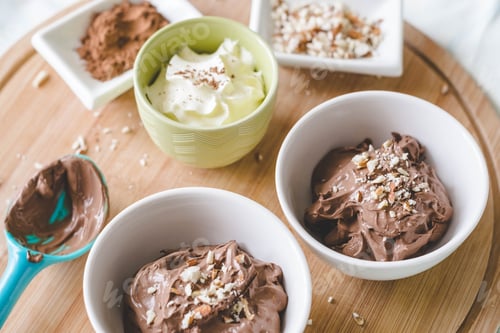 Preview: Homemade Chocolate Low Carb Ice Cream In A Bowl With A Spoon, Cream, Almonds And Cocoa Powder