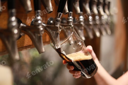 Preview: Hand Of Bartender Pouring A Large Lager Dark Beer In Tap.