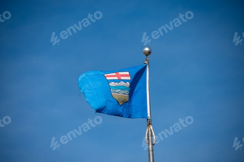Preview: Tattered Alberta Flag Against Blue Sky.