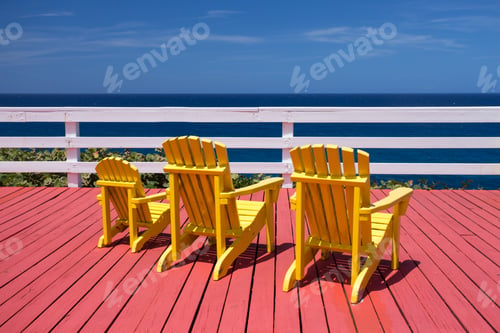 Preview: Three Adirondack Chairs On A Red Deck Overlooking The Ocean