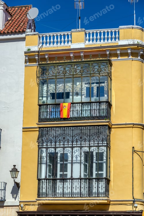 Preview: Yellow Building Balconies with Decorative Ironwork and Flag
