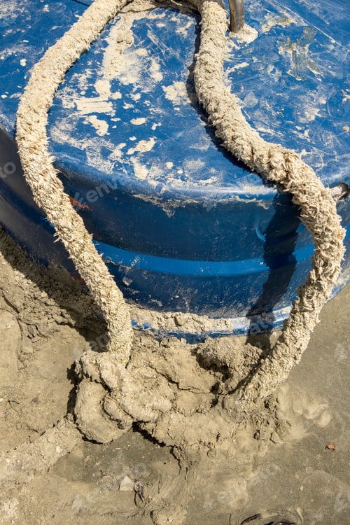 Preview: An Old Rope And Blue Container Abandoned On The Sand Of Beach. Close-Up Of An Old Dirty And