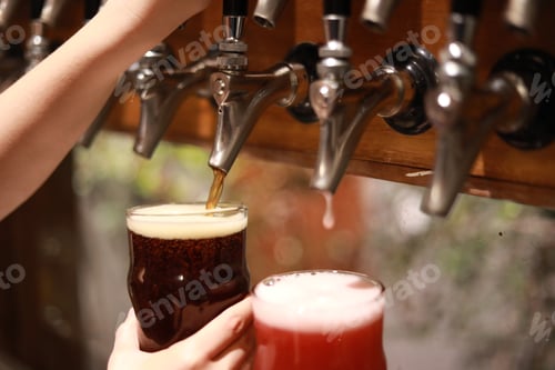 Preview: Hand Of Bartender Pouring A Large Lager Dark Beer In Tap.