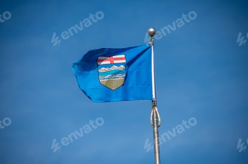 Preview: Tattered Alberta Flag Against Blue Sky.