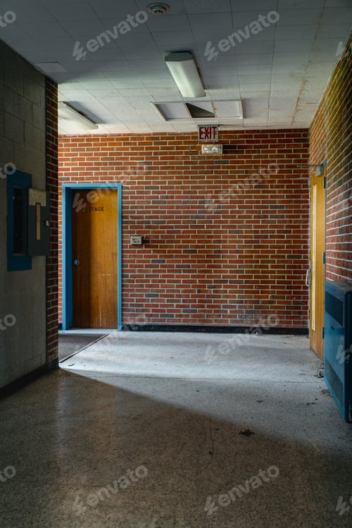 Preview: An Interior View Of A Derelict Hallway Leading To A Door Marked Stage At An Abandoned School.