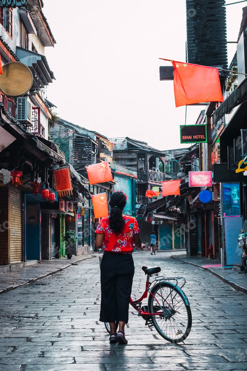 Preview: Woman Cycling In China Ancient Town Yangshou. Street With Stone Floor.