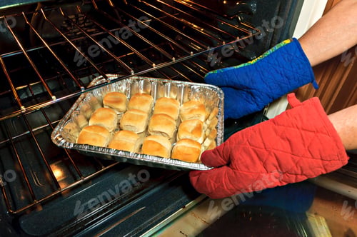 Preview: A Set Of Baked Buns Being Removed From An Oven In Preparation For Dinner.