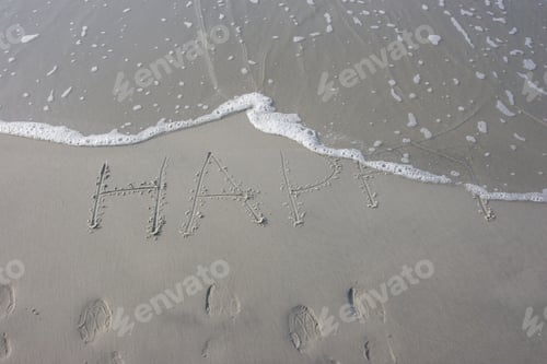 Preview: The Word "Happy" Written In The Sand At The Beach With The Ocean Water Advancing Over It