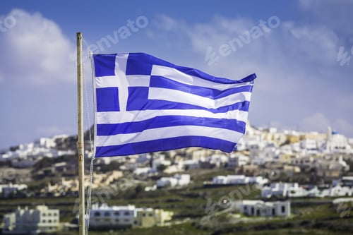 Preview: Waving Greek Flag With Blur Overview Of Santorini Island In Greece