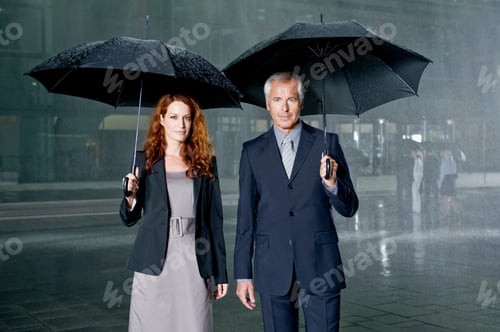 Preview: Two Businesspeople Standing In The Rain Holding Umbrellas