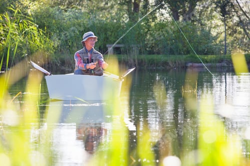 Preview: Front View Of An Elderly Man Fishing Over A Lake While Sitting In A Rowboat With Grass Blades In