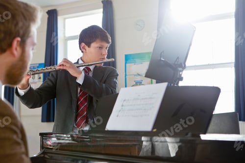 Preview: Middle School Student Playing A Flute With His Teacher Playing The Piano During A Music Class.