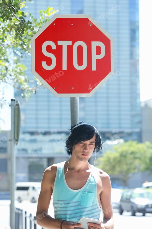 Preview: Portrait Of A Young Man Standing Under A Stop Sign And Using A Digital Tablet