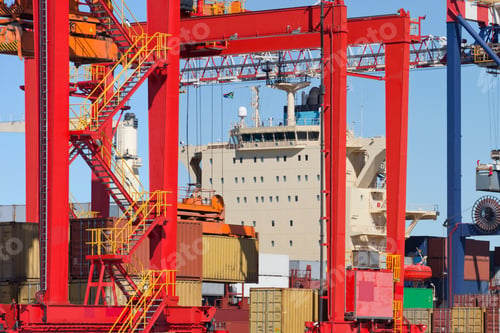 Preview: Wide Shot A Crane Unloading Cargo Containers At A Commercial Dockyard With A Ship In The Background.