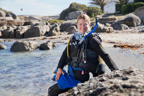 Preview: Woman In Wetsuit Going Ocean Scuba Diving From Rocky Beach And Smiling At Camera