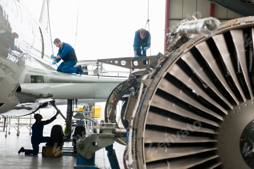 Preview: Engineers In Safety Vests Assembling The Wing Of A Passenger Jet At A Hangar.