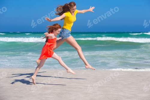Preview: Mother And Daughter Leaping In The Air On A Sunny Beach With Their Arms Outstretched.