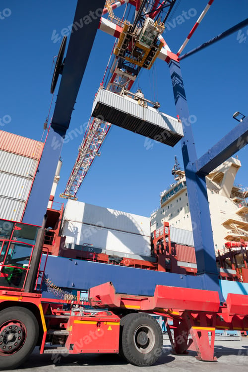 Preview: Vertical Shot Of A Lorry Standing Under A Gantry Crane Ready To Be Loaded With A Cargo Container