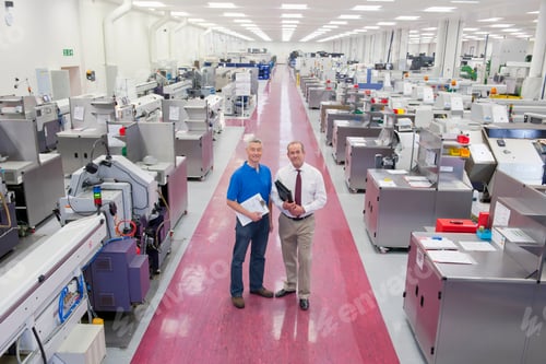 Preview: Wide Shot Of An Engineer And A Businessman Standing In The Aisle Of A Manufacturing Plant And