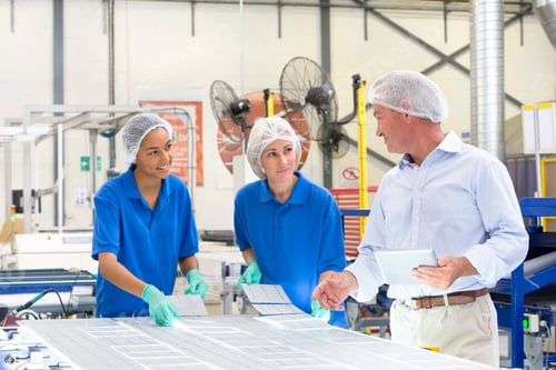 Preview: Businessman Talking To Technicians As They Place Solar Cells On The Panel In The Factory