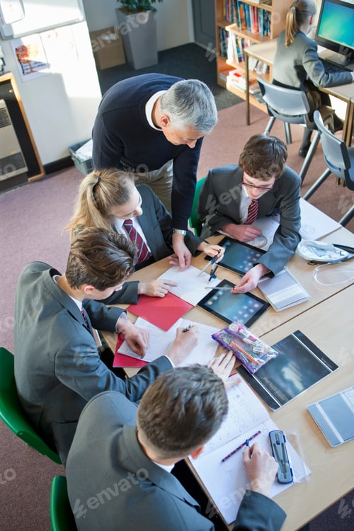 Preview: High Angle Shot Of High School Students Studying In A Classroom With Their Teacher Guiding Them.