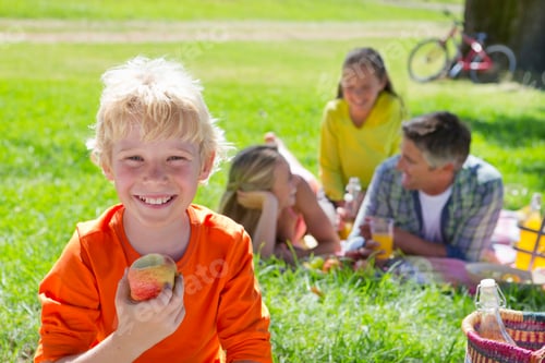 Preview: Portrait Shot Of A Boy Eating An Apple With His Family In The Background.