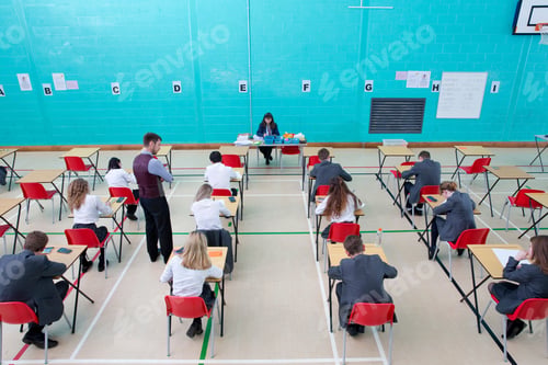 Preview: Wide Shot Of Teachers Supervising Middle School Students Taking Examination At Desks In School