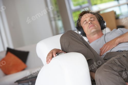 Preview: Man Relaxing In Armchair At Home, Wearing Headphones, Listening To Mp3 Player, Eyes Closed (Tilt)